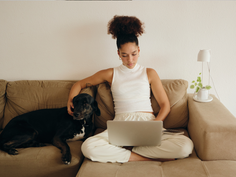 An animal writer works on her laptop next to her dog