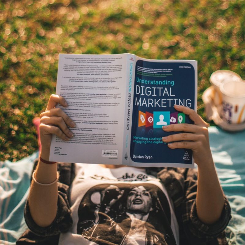 Woman lying on her back reading a book called 'understanding digital marketing' which represents the blog's purpose - to help business owners understand the most effective digital marketing services for pet businesses